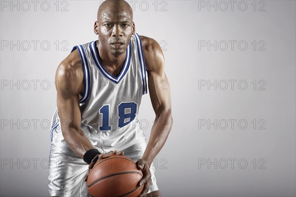 Sweating Hispanic basketball player holding basketball