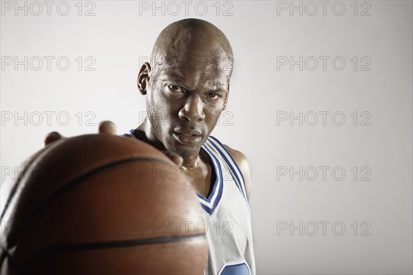 Sweating Hispanic basketball player holding basketball