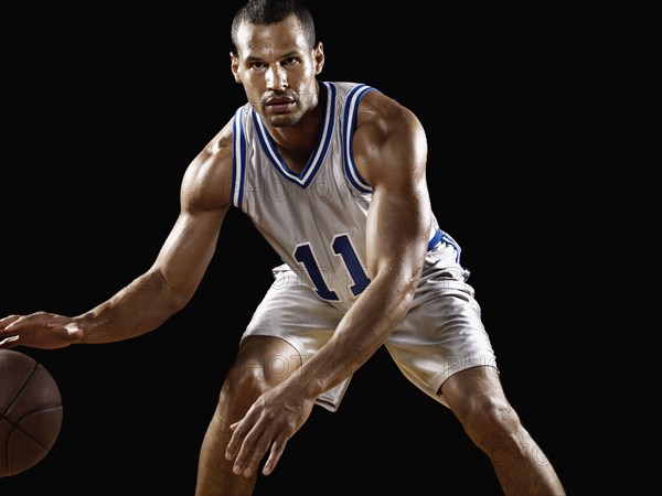 Mixed race basketball player bouncing basketball