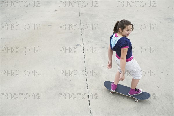 Mixed Race girl riding skateboard