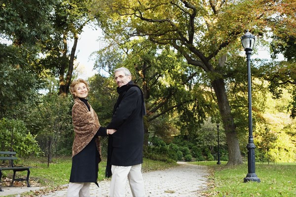 Senior couple walking and holding hands in park