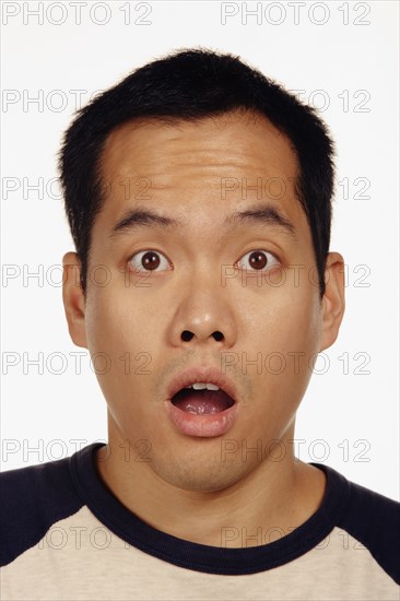 Close up studio shot of Asian man looking surprised