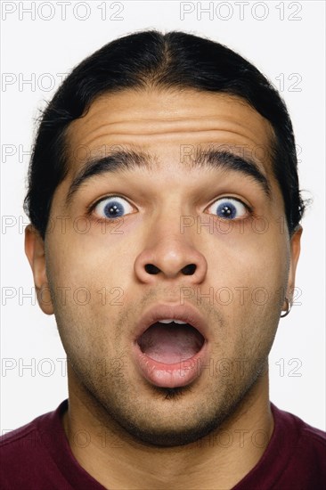 Close up studio shot of Hispanic man looking surprised