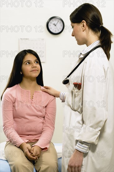Female doctor with hand on young female patient's shoulder