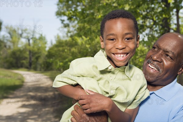 African grandfather holding grandson in park