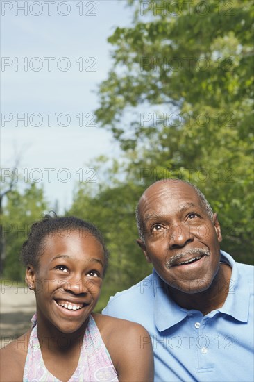 African grandfather and granddaughter looking up in park