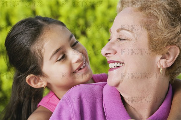 Hispanic grandmother and granddaughter smiling at each other