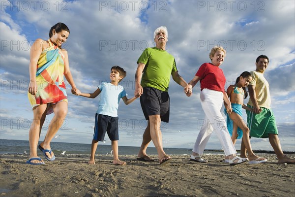 Low angle view of Hispanic family holding hands at beach