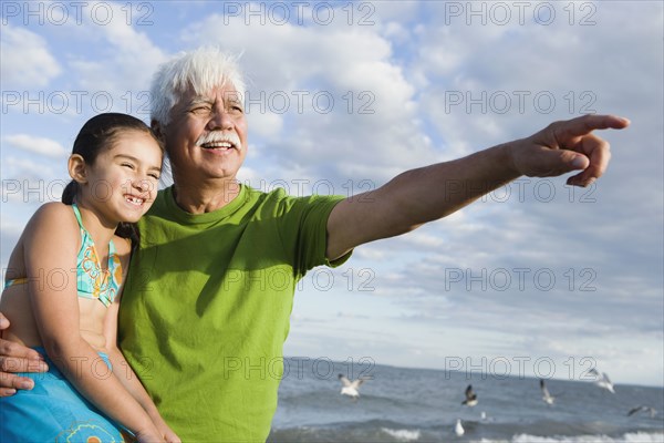 Hispanic grandfather with granddaughter pointing into the distance