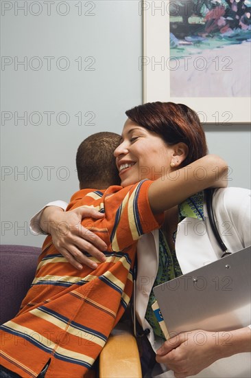 Hispanic female doctor hugging at boy in waiting room