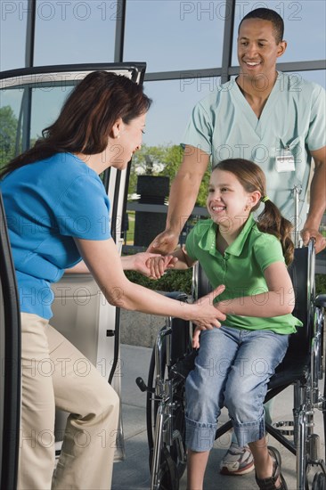 Hispanic girl in wheelchair leaving hospital with mother