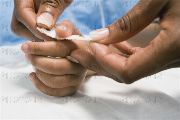 Close up of African nurse putting adhesive bandage on child's thumb