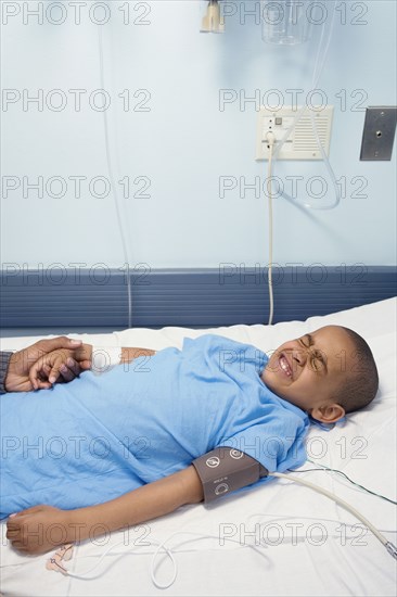 African boy laying in hospital bed wincing