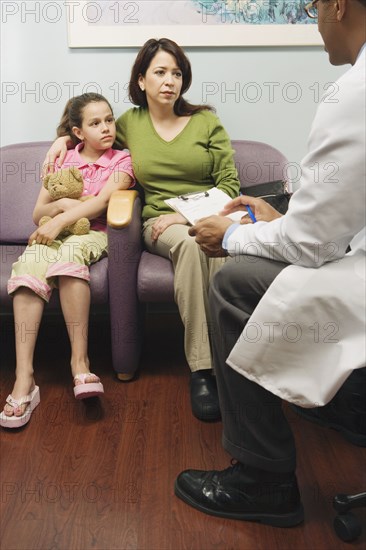 Doctor talking to Hispanic mother and daughter in waiting room