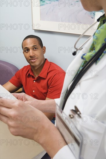 African man talking to doctor in waiting room