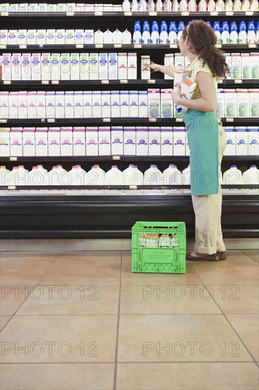 Mixed Race woman stocking shelves at grocery store