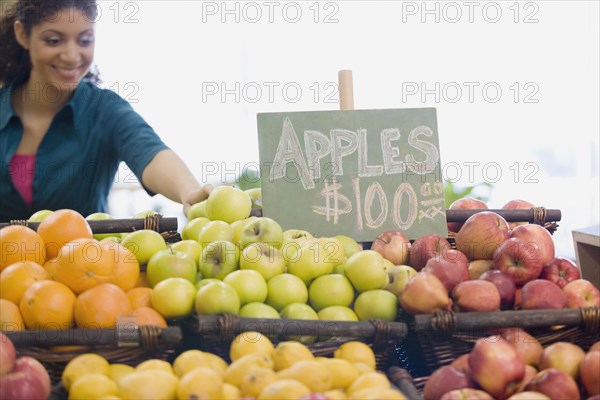 Mixed Race woman choosing apples at grocery store