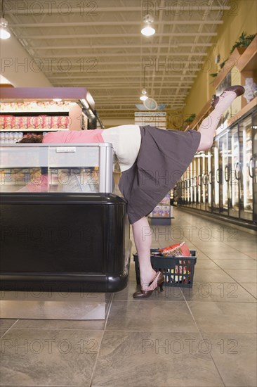 Woman leaning into display at grocery store