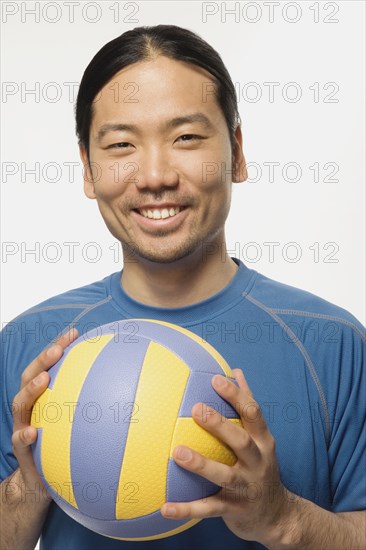 Asian man holding volleyball