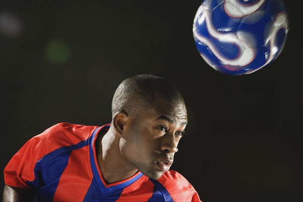 African American man bouncing soccer ball on head