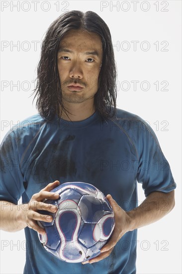 Asian male soccer player holding ball