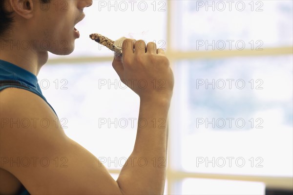 Asian man eating energy bar