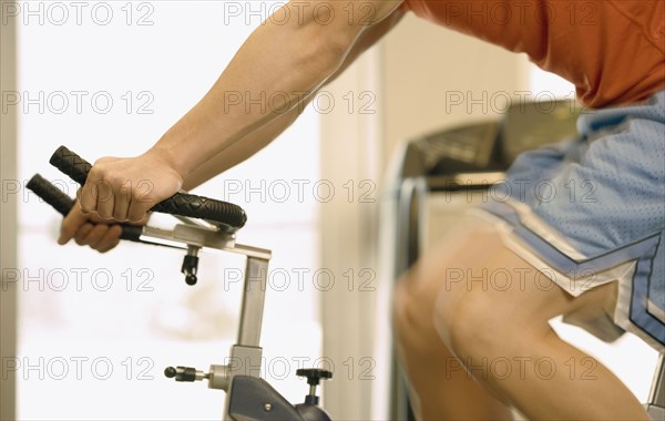 Asian man riding on exercise bicycle