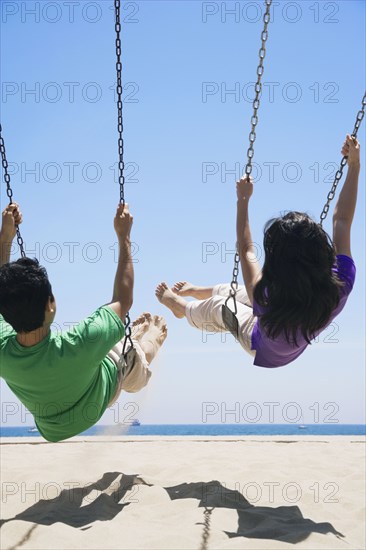 Asian couple swinging at beach