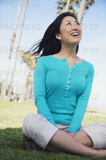 Asian woman sitting on grass