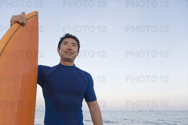 Asian man holding surfboard