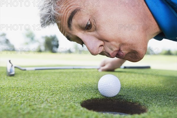 Man blowing on golf ball