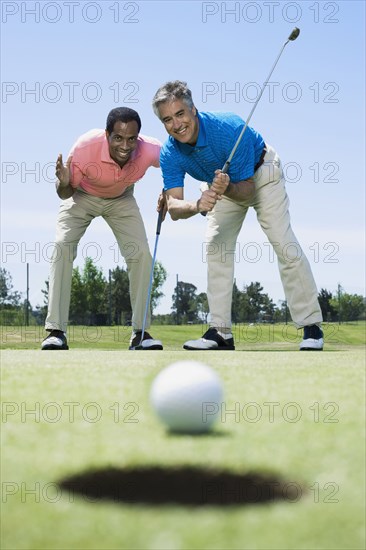 Multi-ethnic men looking at golf ball