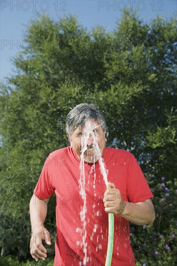 Hispanic man spraying hose on face