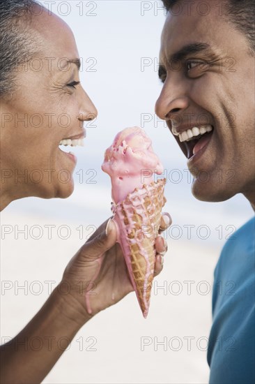 Multi-ethnic couple eating ice cream cone