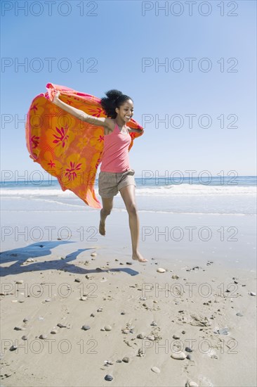 African woman running with beach towel