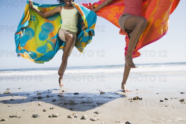 African sisters running with beach towels