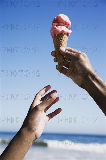 African girl reaching for ice cream cone