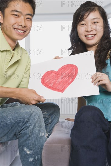 Chinese couple holding paper with heart