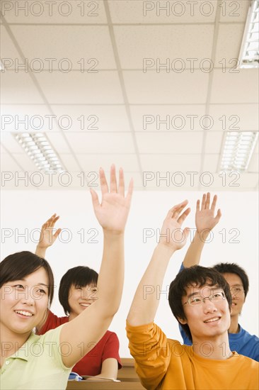 Chinese students with arms raised in classroom