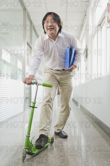 Chinese man riding scooter in corridor