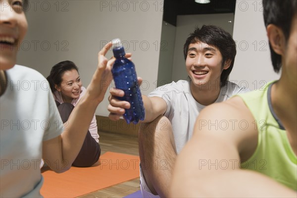 Chinese man handing woman water bottle in exercise class