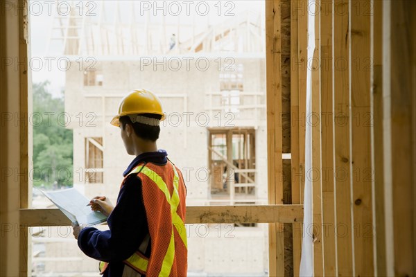 Chinese construction worker writing on clipboard