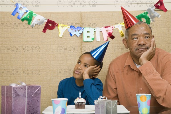 African boy with grandfather and cupcake at birthday party