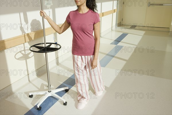 Woman walking down hospital hallway with iv drip