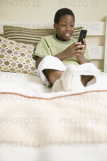 African American boy text messaging on cell phone