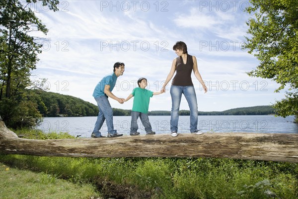 Parents helping son walk across log