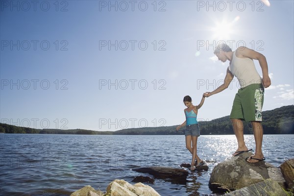 Father and daughter standing by lake