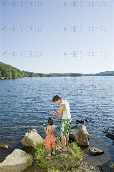 Mixed race father and son fishing in lake