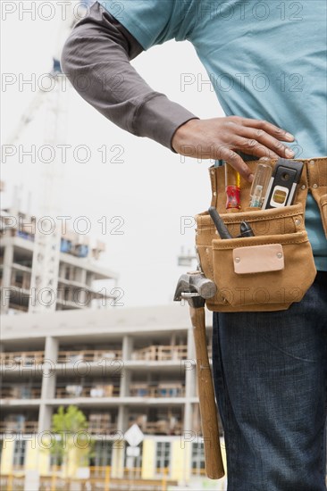 Black construction worker wearing tool belt