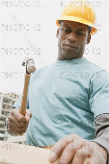 Black construction worker hammering wood